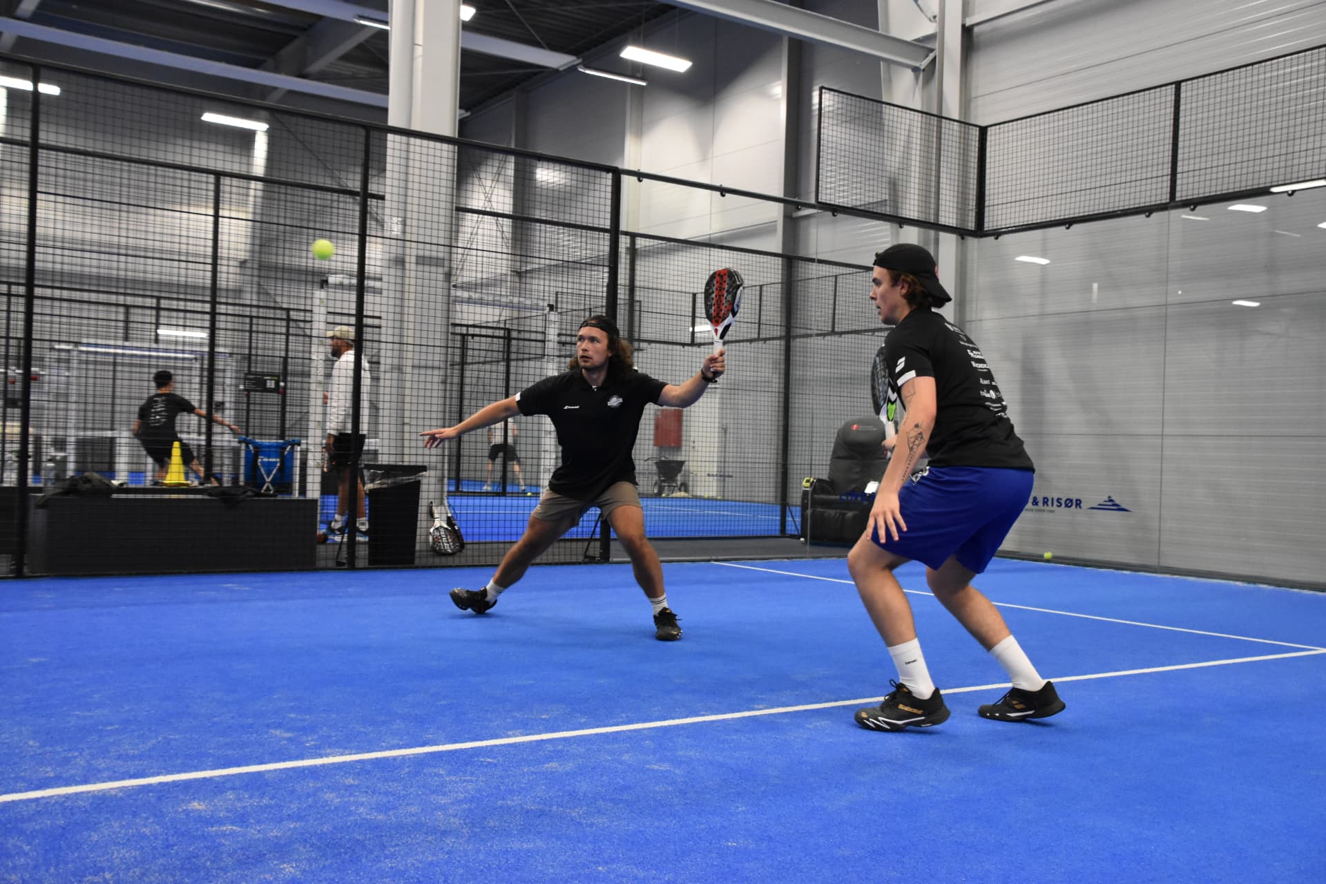 Spillere i aktion på en solbeskinnet padelbane